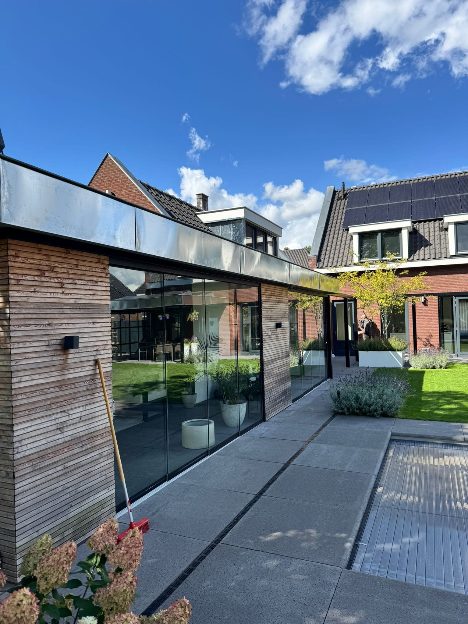 Moderne glazen aanbouw met een zinken dakrand langs het platte dak
